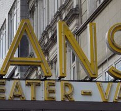  Gelbgoldene Großbuchstaben bilden das Wort 'HANSA' auf einem Vordach. Darunter steht in etwas kleineren, ebenfalls gelbgoldenen Buchstaben 'THEATER – VARIETE'. Dahinter ist eine helle Fassade mit Fensterreihen.