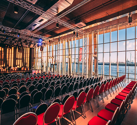 Blick in den Saal Richtung Bühne mit Blick aus der Fensterfront auf die Elbe