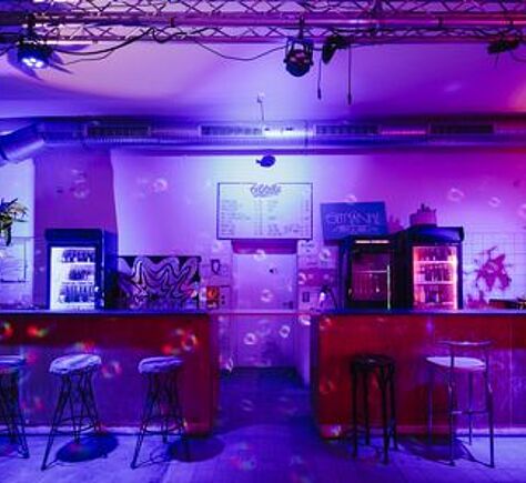 ein lila ausgeleuchteter niedriger Raum mit Bar